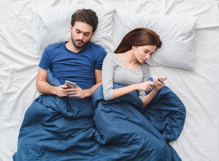 Young couple in bed top view morning concept phone addictedの写真素材