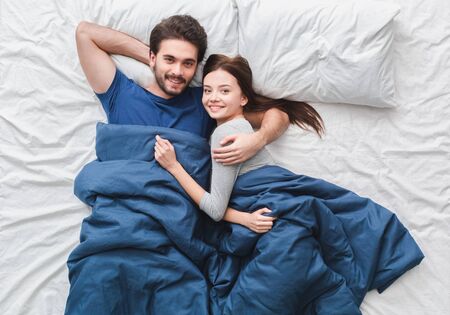 Young couple in bed top view morning concept hugging relaxedの写真素材