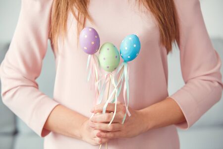 Young woman at home easter celbration concept holding decorative eggs on sticks close-upの写真素材