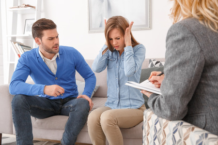 Young couple with psychologist family therapy wife covering earsの写真素材