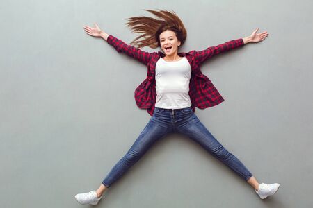 Young woman top view isolated on grey lying on floor cheerfulの写真素材