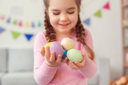 Little cute girl easter celebration at home concept standing holding eggs close-up blurred backgroundの写真素材