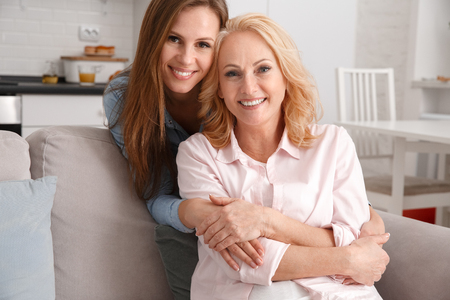 Mother and daughter together at home weekend hugging looking cameraの写真素材