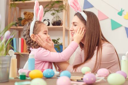 Mother and daughter together at home easter preparation in bunny ears sitting holding each other...