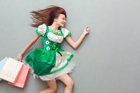 Young woman in a festive dress saint patricks day top view walking with shopping bagsの写真素材
