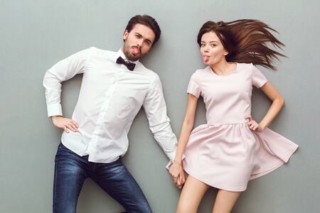 Young couple top view isolated on grey background tongues out grimaceの写真素材