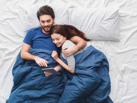 Young couple in bed top view morning concept watching movie on digital tabletの写真素材