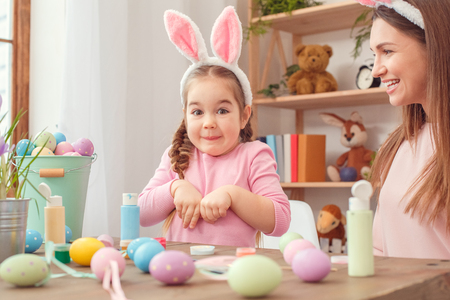 Mother and daughter together at home easter preparation in bunny ears sitting girl playing hareの写真素材