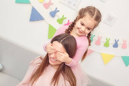Mother and daughter weekend together at home girl making surpriseの写真素材