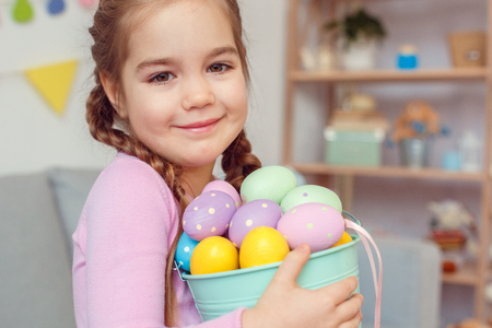 Little cute girl easter celebration at home concept holding bucket with eggsの写真素材