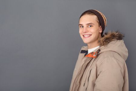 Young man studio isolated on grey winter style looking camera happyの写真素材
