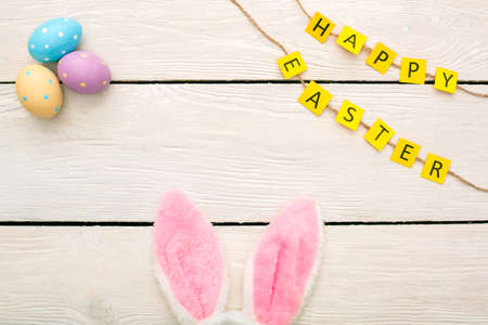 Easter traditional objects isolated on wooden floor bunny ears at the bottom happy easter top viewの写真素材