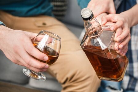 Boy and father alcoholic at home son stopping dad fron drinking whiskey hands close-upの写真素材