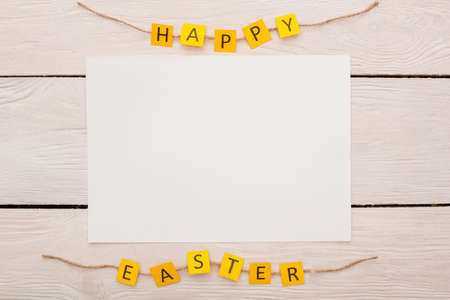 Happy easter yellow letters isolated on wooden background and white sheet of paperの写真素材