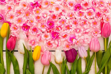 Spring decorations objects isolated on wooden floor stewn with many colorful flowersの写真素材