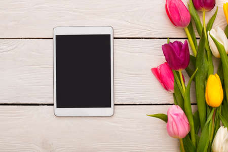 Spring decorations flowers isolated on wooden floor and digital tablet advertisement spaceの写真素材