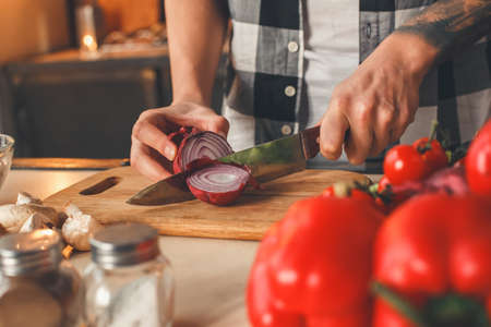 Man sliced violet onion, preparing salad. Indoor, kitchen home interior, studio shot.の写真素材