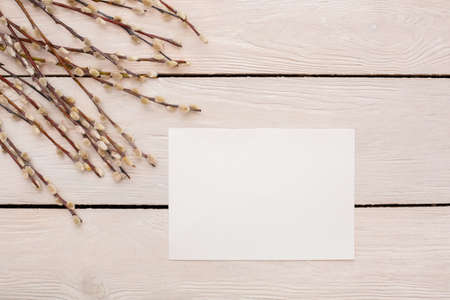 Easter traditional objects isolated on wooden floor willow branches and white empty paperの写真素材