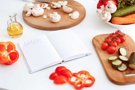 Lot of vegetables on the table and a notebook with an inscription cooking. Indoor, studio shoot, kitchen interiorの写真素材