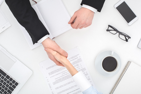 Two business people sitting at office top view close-up shaking hands partnership agreementの写真素材