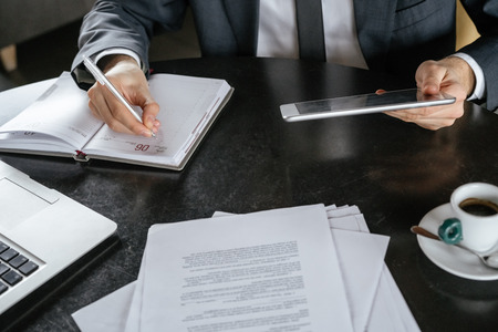 Businessman on business lunch at restaurant sitting at table close-up holding digital tablet taking...