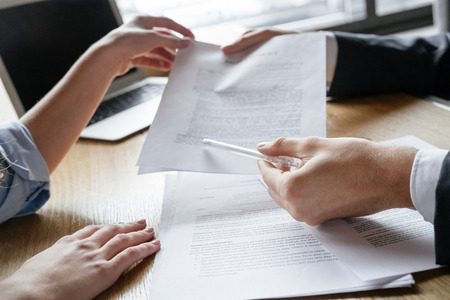 Man and woman having business lunch at restaurant sitting at table holding contract discussing term and conditionds close-upの写真素材
