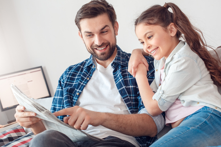 Father and little daughter at home sitting man showing daughter news cheerfulの写真素材