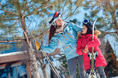 Winter vacation. Family time together outdoors woman and girl in goggles with skis looking at each other happy close-upの写真素材