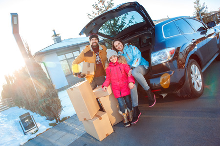 Moving to new apartment. Family together outdoors standing sitting at car with boxes smiling happyの写真素材