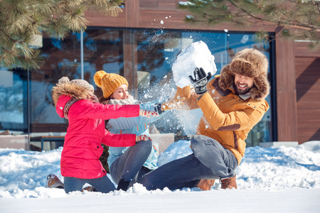 Winter vacation. Family time together outdoors sitting throwing snow fighting laughing surprised...