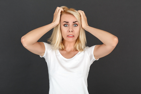Freestyle. Woman standing isolated on black wall holding hair nervous close-upの写真素材