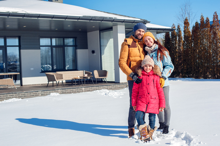 Winter vacation. Family time together outdoors standing near house hugging smiling cheerfulの写真素材