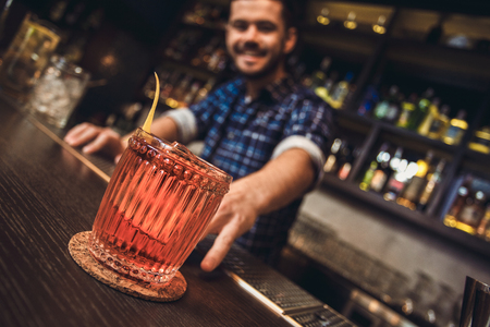 Young bartender standing at bar counter cocktail close-upの写真素材