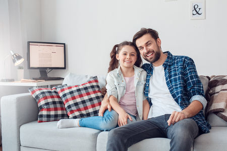 Father and little daughter at home sitting hugging smiling relaxedの写真素材