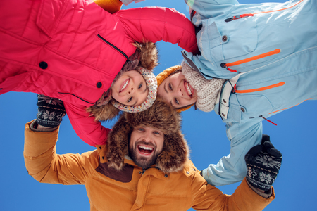 Winter vacation. Family time together outdoors hugging looking camera smiling excited bottom viewの写真素材