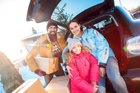 Moving to new apartment. Family together outdoors standing sitting at car with boxes smiling cheerful close-upの写真素材