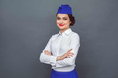 Professional Occupation. Stewardess standing isolated on grey smiling confidentの写真素材