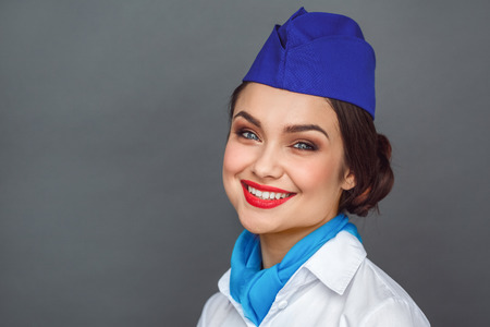 Professional Occupation. Stewardess standing isolated on grey looking camera smiling happy close-upの写真素材