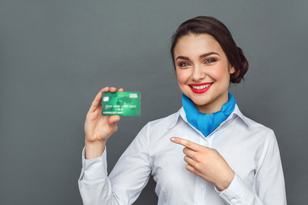 Professional Occupation. Stewardess standing isolated on grey pointing at debit card smiling cheerfulの写真素材