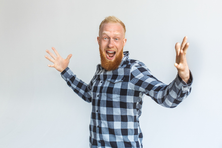Freestyle. Mature man standing isolated on grey hands aside shouting excitedの写真素材