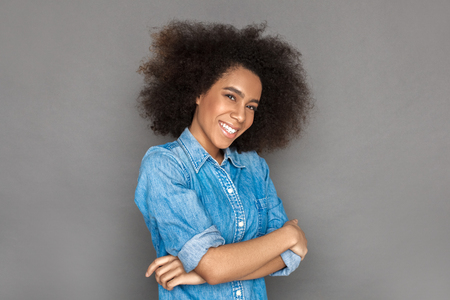 Mulatto woman standing isolated on grey crossed arms laughing shy close-upの写真素材