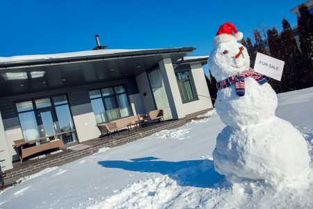 Winter time. Snowman with sale card on a yard near house no peopleの写真素材