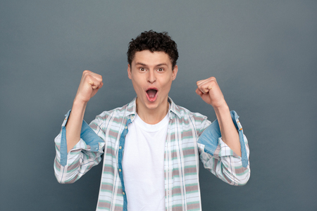 Man isolated on gray wall free style looking camera holding fists cheerfulの写真素材