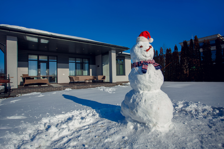 Winter time. Snowman on a yard near house no peopleの写真素材