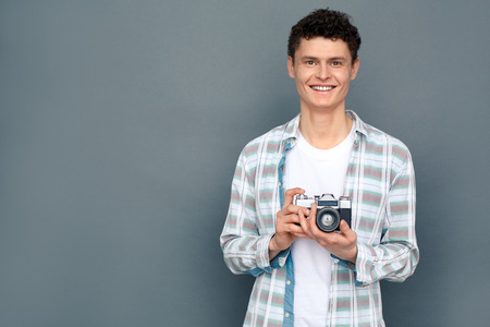 Man isolated on gray wall tourism concept standing holding camera smilingの写真素材