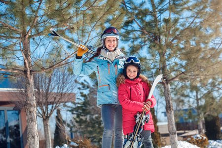 Winter vacation. Family time together outdoors woman and girl in goggles with skis smiling motivatedの写真素材