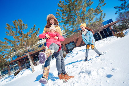 Winter vacation. Family time together outdoors man holding girl spinning laughing happyの写真素材