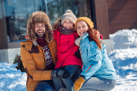 Winter vacation. Family time together outdoors sitting hugging laughing cheerful close-upの写真素材