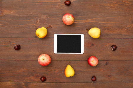Autumn season. Digital tablet fruits and chestnuts isolated on table top view