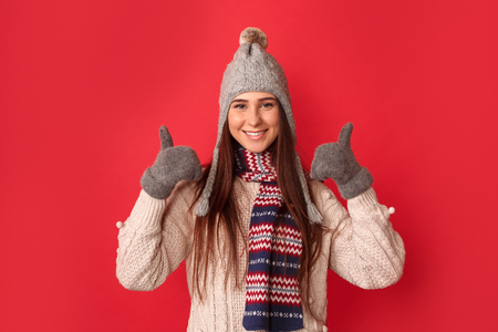 Freestyle. Young woman wearing scarf and hat standing isolated on red thumbs up looking camera cheerfulの写真素材